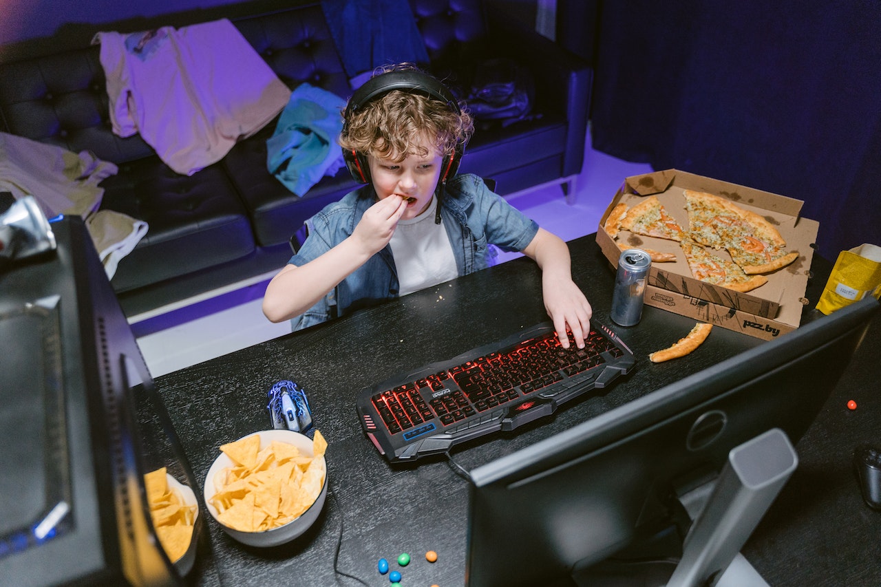 Kid playing video games while listening to music and eating food